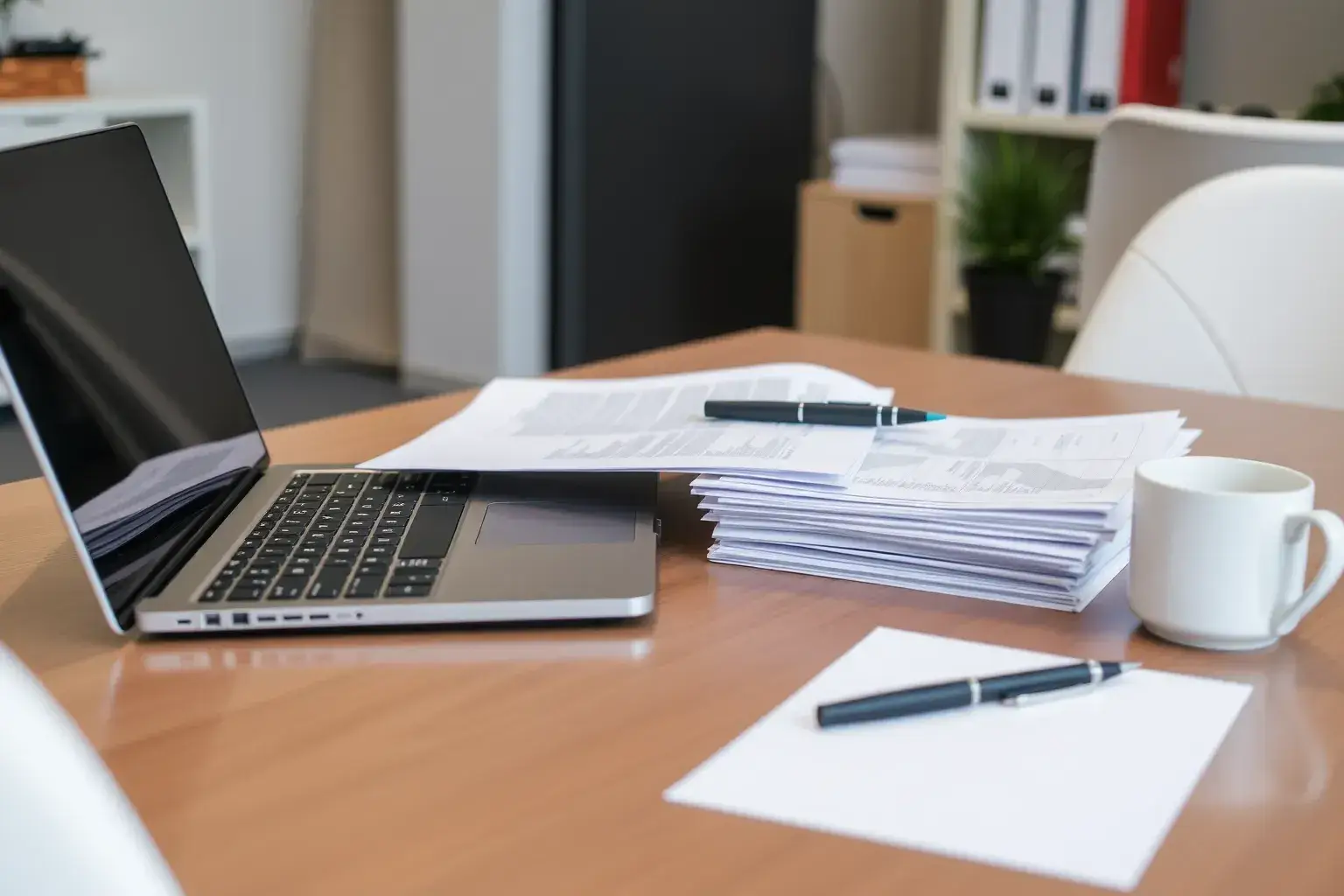 Un bureau avec ordinateur portable et documents empilés.